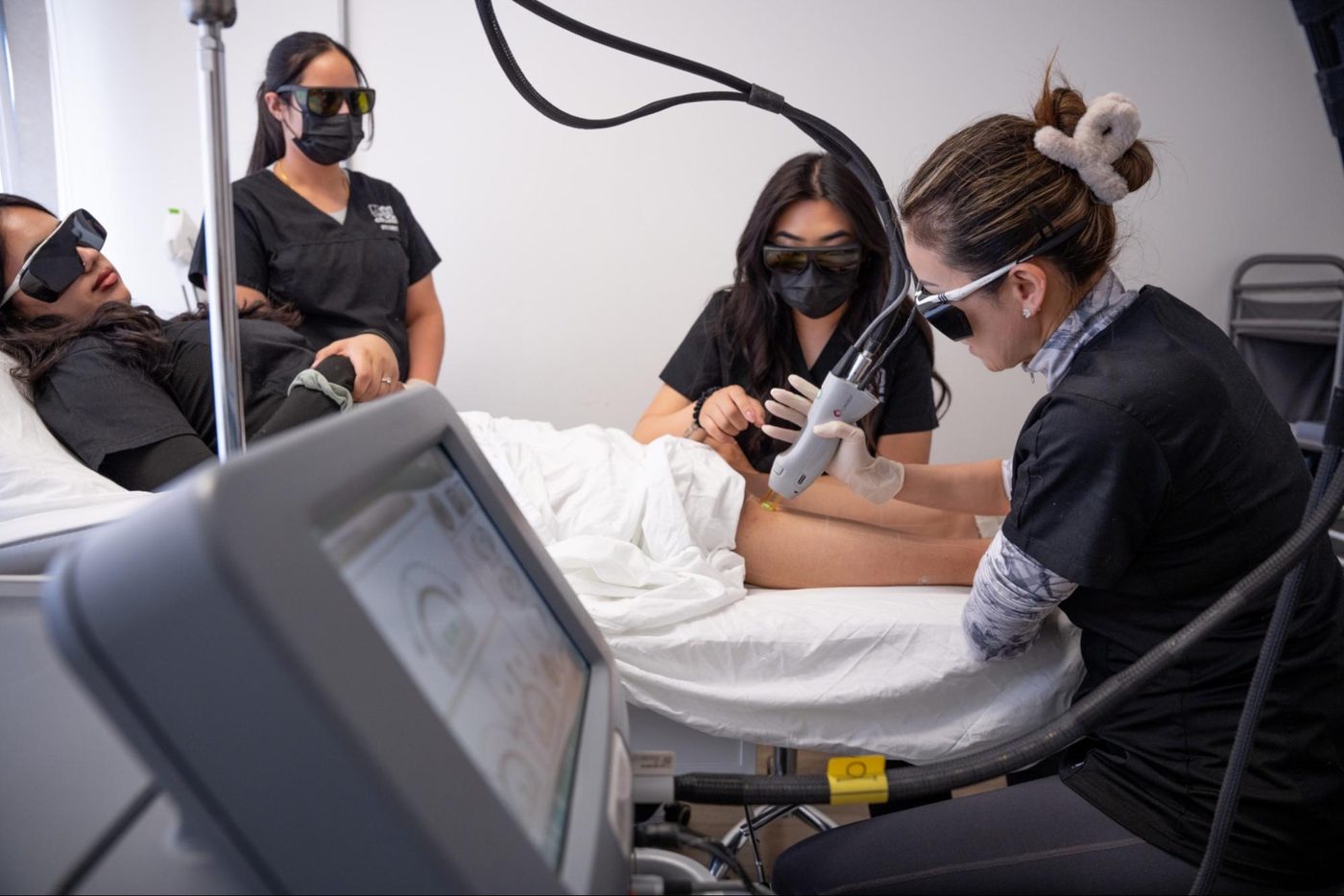 GD College students performing a supervised laser treatment in the clinical esthetics lab