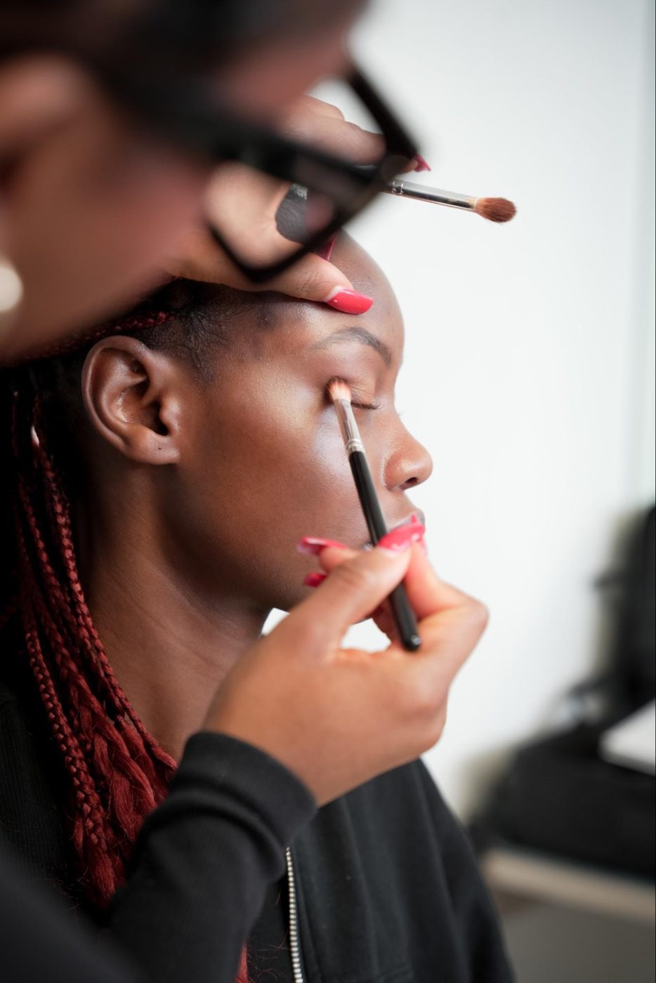 GD College student applying eyeshadow to a model during a makeup artistry class