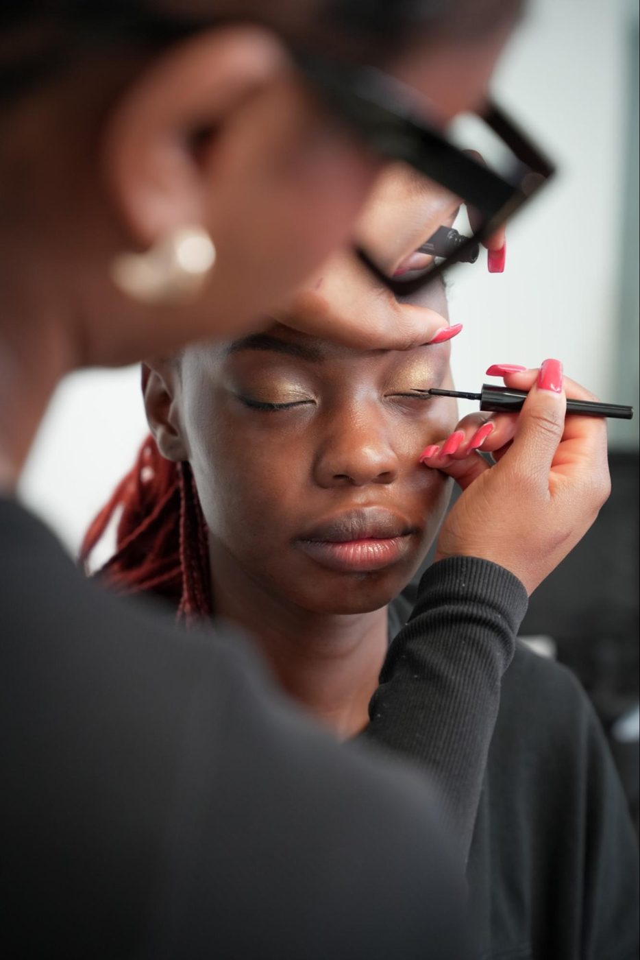 GD College student applying eyeliner to a model during a makeup artistry class