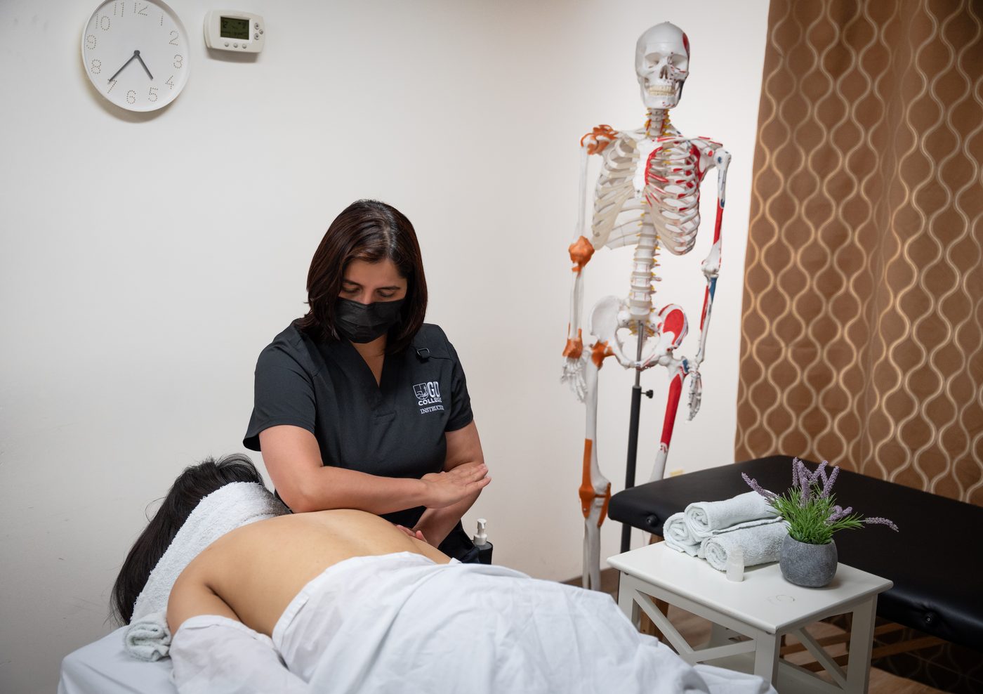 GD College instructor performing a supervised massage therapy treatment in the training clinic